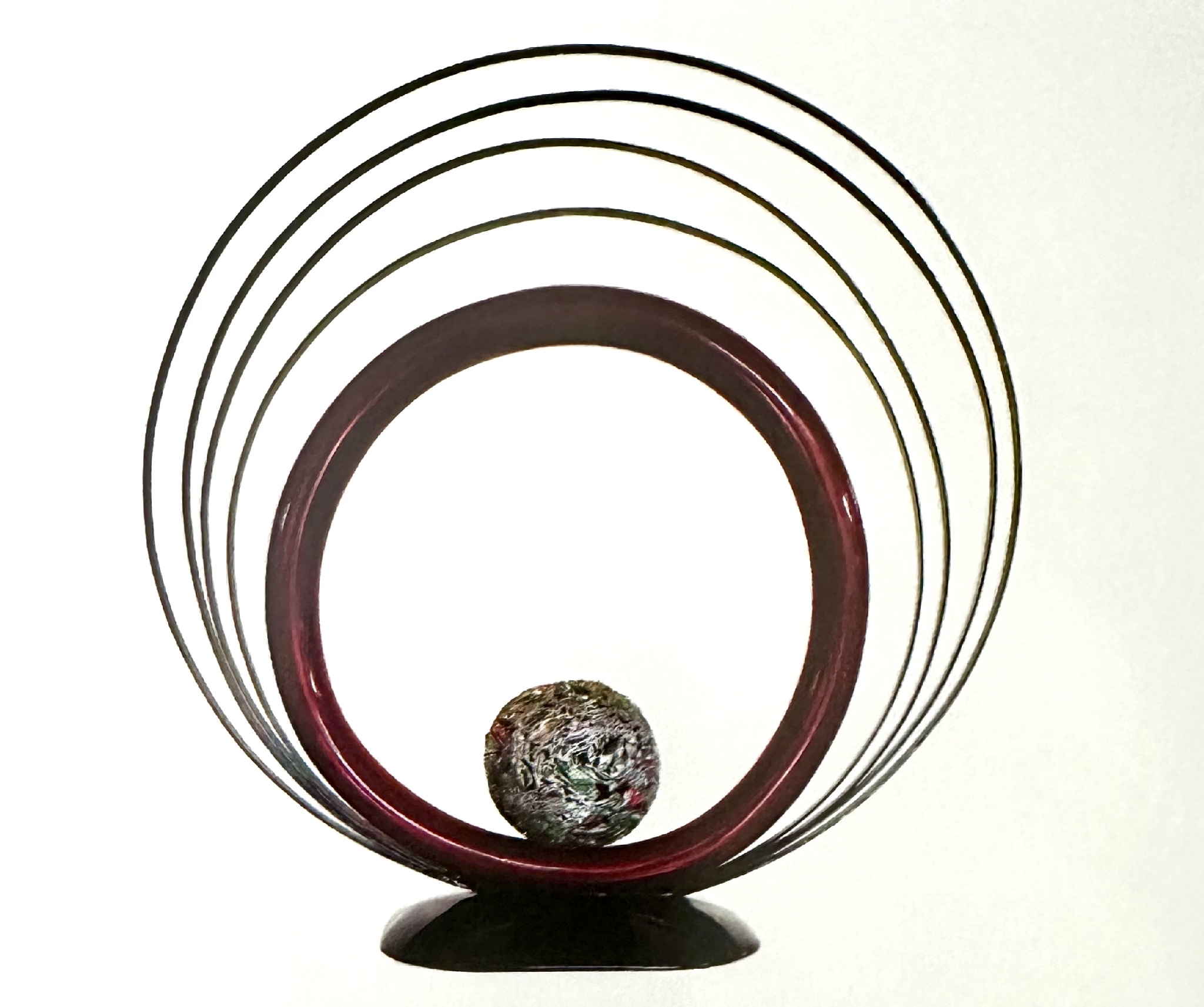 An Iron Sculpture Of A Ball In A Circle With By Artist Ilse De Manazanares.