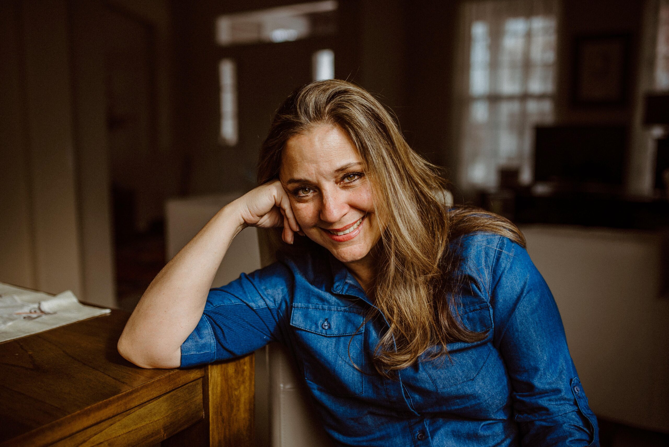Artist Michele Norman Waring A Blue Shirt And Looking At The Camera While Smiling